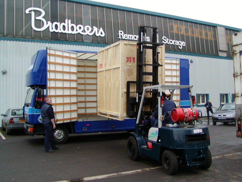 Forklift loading a packing crate onto a large blue van